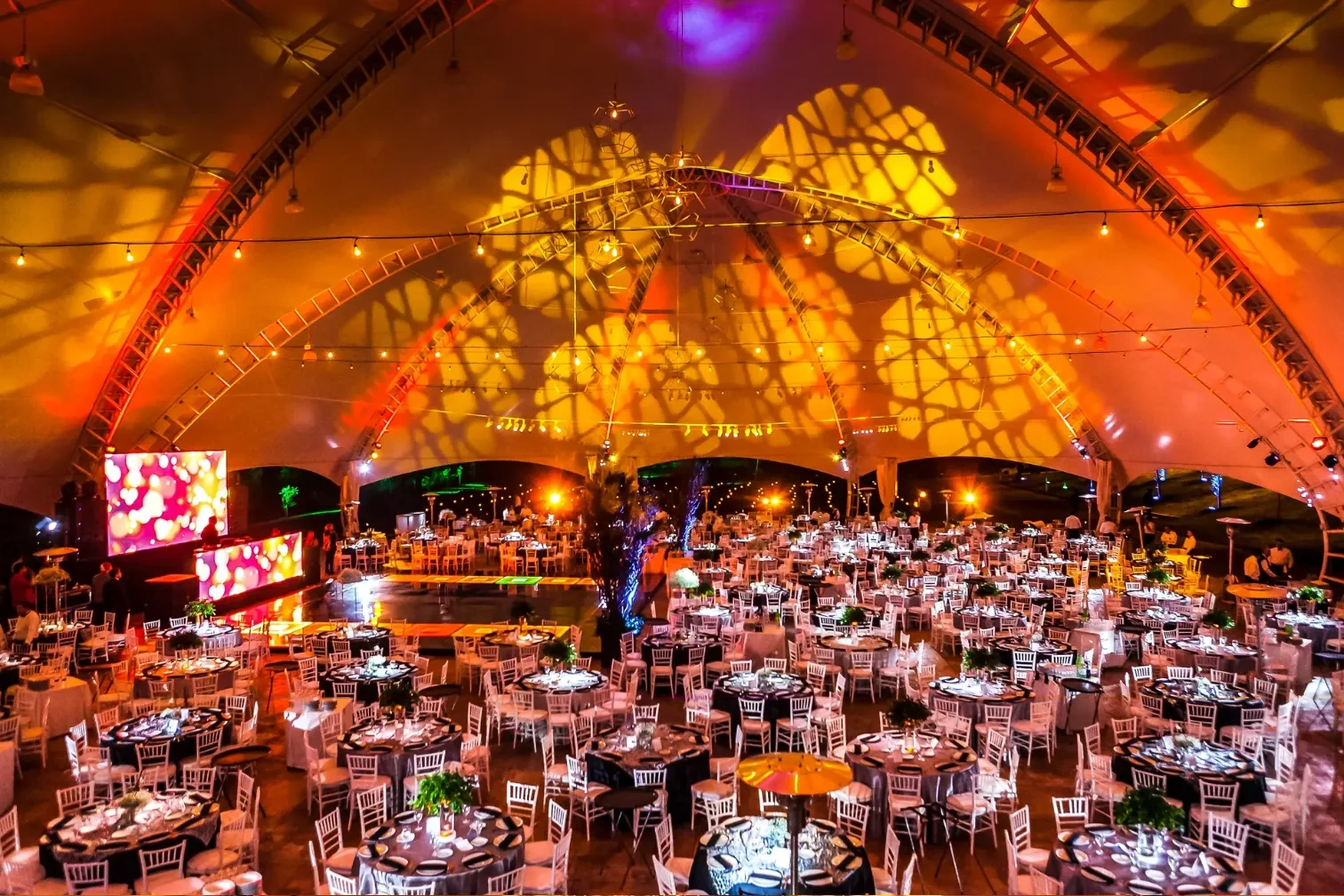 Carpa monumental con proyección cálida y luces colgantes