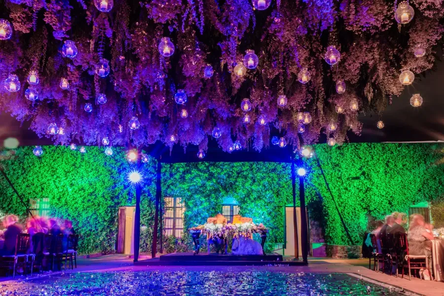 Techo de flores colgantes con esferas de luz sobre la pista y la mesa de novios