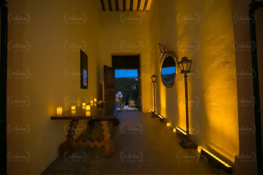 Pasillo con luz rasante cálida, velas y espejo